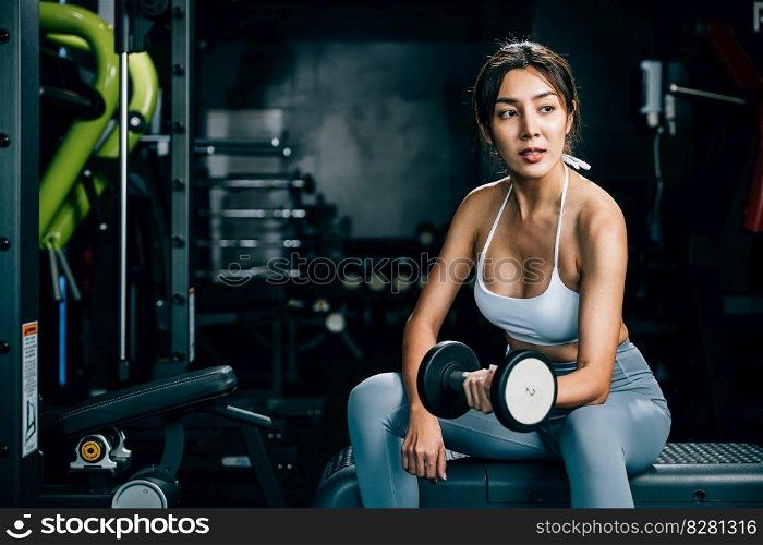 A sporty female engaging in weightlifting training at the gym, using dumbbells to exercise her arms and build up her strength and endurance, fitness GYM dark background