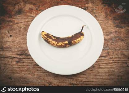 A spotted banana on a white plate