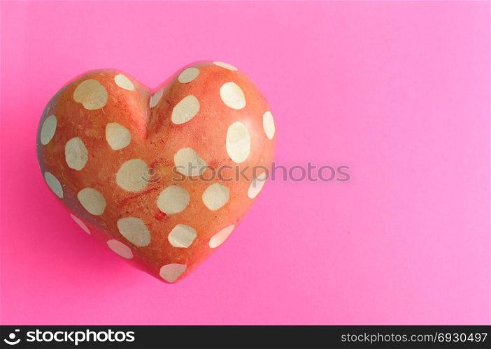 A spotted heart isolated on a pink background