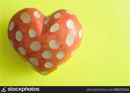 A spotted heart isolated on a yellow background