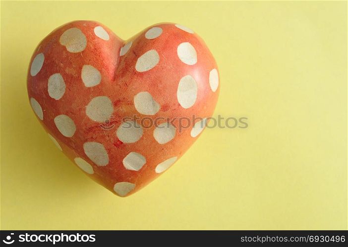 A spotted heart isolated on a yellow background