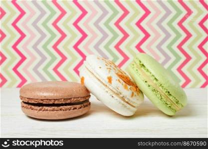 A stack of colorful traditional French dessert makarons on colorful striped background. copy space for text.. French macaroons .Dessert