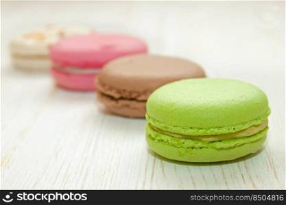 A stack of colorful traditional French dessert makarons on white wooden background.. French macaroons .Dessert
