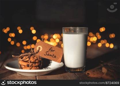 A stack of cookies and glass of milk for Santa on wooden background, concept Christmas and holiday. A stack of cookies and glass of milk for Santa on wooden background