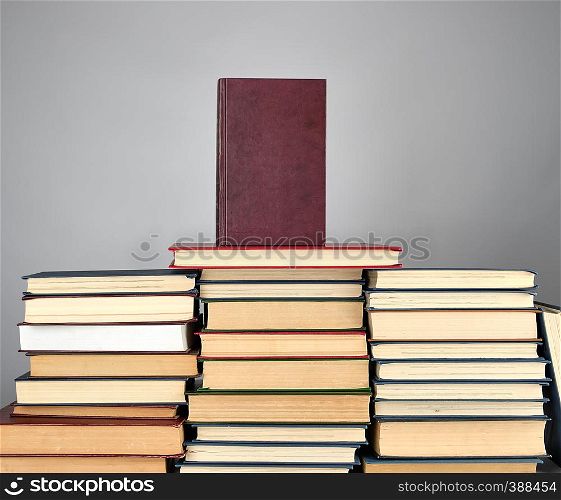 a stack of different books on a gray background, top of a book in red binding