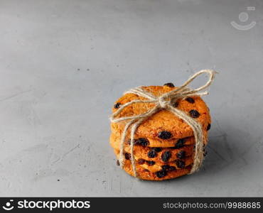 A stack of homemade oatmeal raisin cookies tied in string on a gray concrete surface. Copy space.. Homemade oatmeal cookies are tied with string on a gray concrete surface. Copy space.