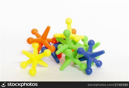 a stack of jacks children's toys, there are green, blue, yellow and pink ones, isolated on white background.