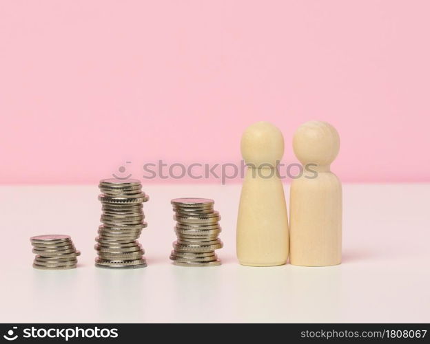 a stack of metal coins and wooden figures of men on a white table. Savings and expenses, family budget, subsidies from the state