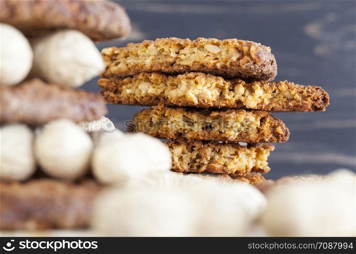 A stack of oatmeal cookies with crushed roasted peanuts and lying on a wooden table next to whole nuts of inshell peanuts, some cookies are broken and crumbs lie. cookies with crushed roasted peanuts