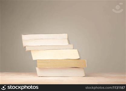 A stack of old books resting on a dusty desk in room.