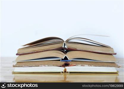a stack of open books on a wooden table on a white background