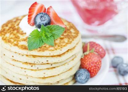 A stack of pancakes decorated with ripe raspberries and sour cream close-up