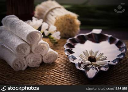 A stack of white towels and a container of water and a flower. Accessories for spa. A stack of white towels and a container of water and a flower.