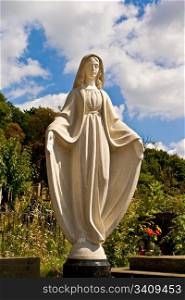 A statue of saint Mary over blue sky