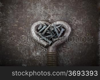 A steel heart is full of nails on a metal background