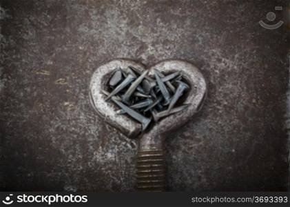 A steel heart is full of nails on a metal background