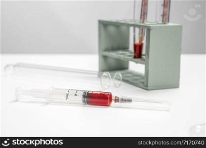 a sterile syringe with a blood sample on a white medical table. selective focus and small focus area