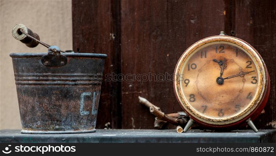 a still life with a small bucket and an alarm clock