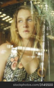 A stock photo of a woman looking scared through broken glass