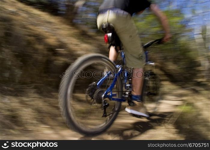 A stock photograph of an active young man riging through the country on a mountain bike.