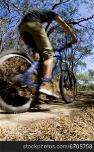 A stock photograph of an active young man riging through the country on a mountain bike.