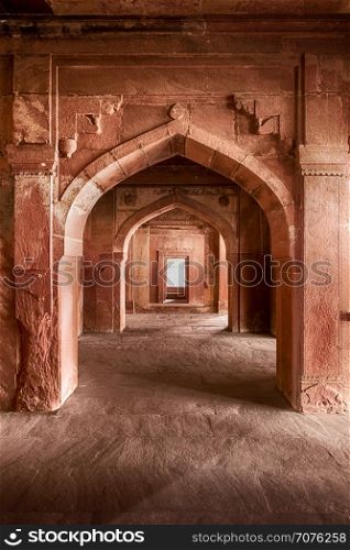 A stone arch of red sandstone leads out of the Emperor&rsquo;s bed chamber to an outdoor courtyard in the ancient Mughal city of Fatehpur, India.
