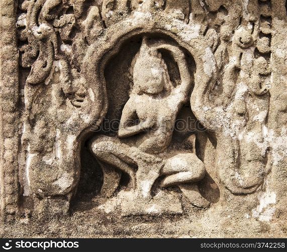 A stone carving of an apsara dancing in a stone niche at the Bayon in Angkor Thom. The carving in the soft rock has been eroded over centuries so that the features are starting to become indistinct.