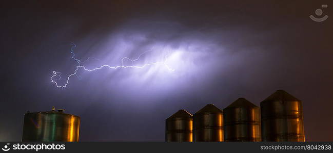 A storm passes over large metal containers releasing electrical charge