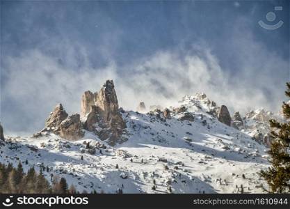 a stormy snowstorm over the Italian Dolomite summit called cigolade with its typical rock formations in the near of vigo in the fassa valley. Stormy snowstorm over the Dolomite summit called cigolade