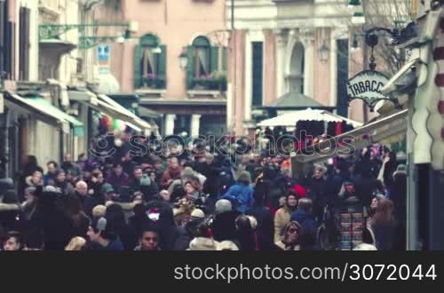 A stream of people walking in the city street among old vintage buildings. Venice is a popular touristic place in Europe