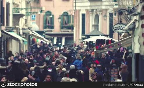 A stream of people walking in the city street among old vintage buildings. Venice is a popular touristic place in Europe