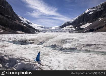 A stream of water runs off the Athabasca Glacier in the summer. The icefall from the Columbia Ice Cap is in the background.