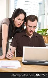 A stressed couple paying bills by using online banking at home