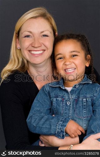 A studio shot of a happy smiling beautiful young mixed race little girl and a caucasian woman in her thirties