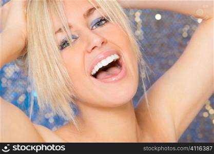 A stunningly beautiful young blonde model laughing in front of an electric blue background