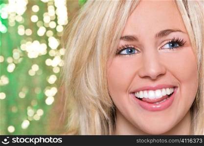 A stunningly beautiful young blonde woman with a gorgeous toothy laugh shot against a sparkling green background