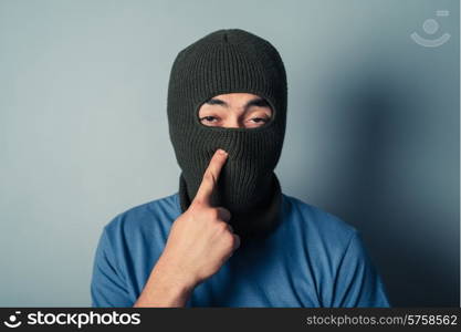 A stupid man wearing a balaclava is trying to pick his nose
