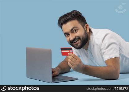 A STYLISH BEARDED MAN LOOKING AT CAMERA WHILE HOLDING DEBIT CARD