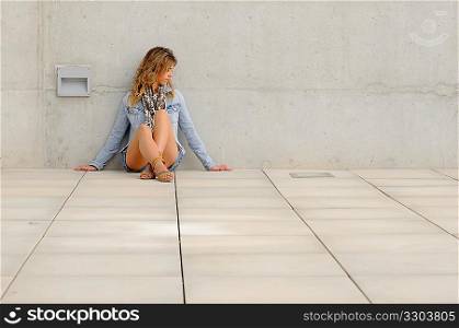 A stylish woman dressed in denim leaning against a wall