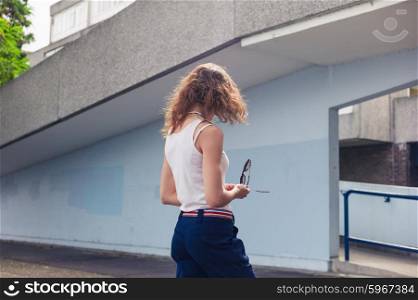 A stylish young woman is standing in the yard of a housing estate