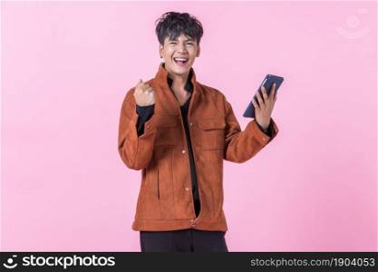a successful and Express joy Asian a man handsome young using a tablet to the side eyes looking at camera in love isolated on pink blank copy space studio background.