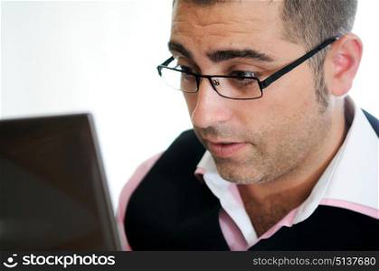 A successful businessman with glasses wearing vest and pink shirt looking at a little computer