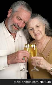 A successful middle aged couple celebrating with glasses of champagne. Isolated on black.