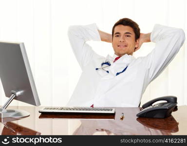 a successful young doctor sitting at desk, smiling.