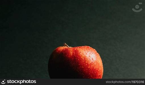 A super close up of a delicious apple with some water drops over it over a dark background with copy space