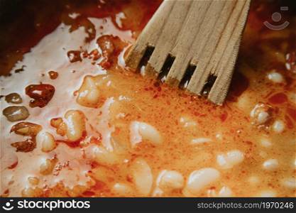 A super close up of a spanish fabada with a wooden spoon