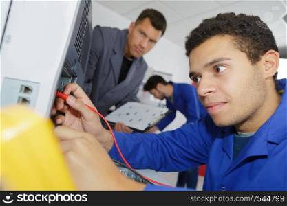 a supervisor watching apprentice electrician