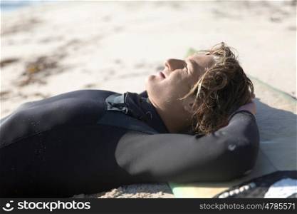 A surfer relaxing and lying on his surfboard at the beach
