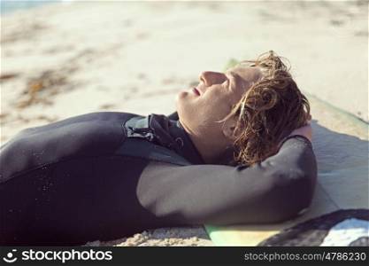 A surfer relaxing and lying on his surfboard at the beach