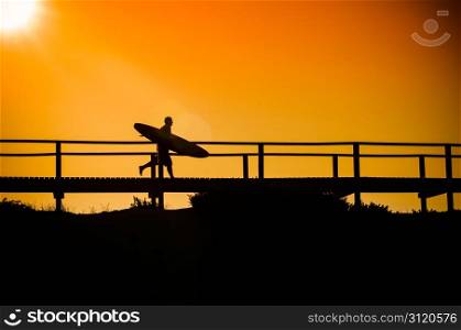 A surfer running to the beach at sunset in Portugal.